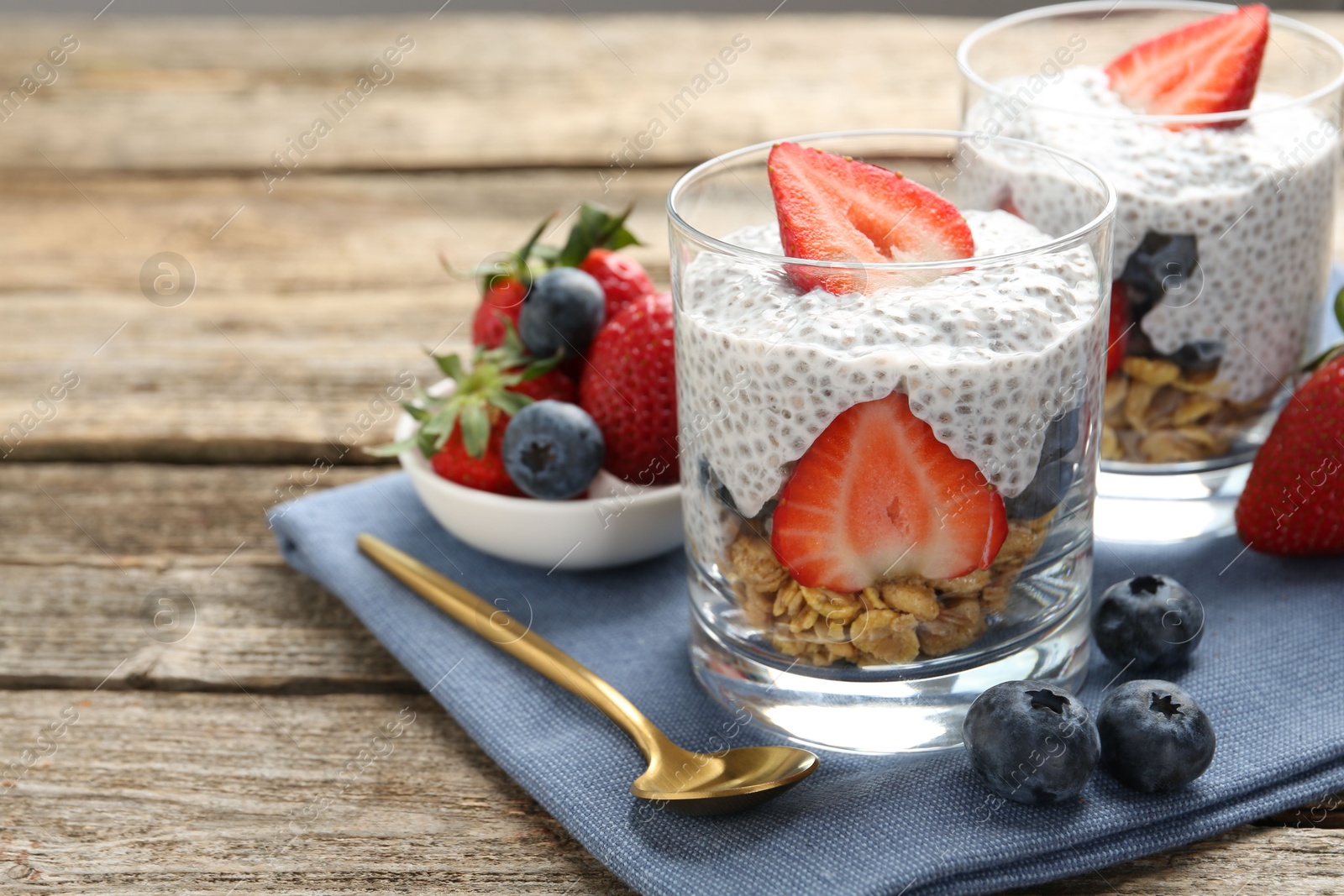 Delicious dessert with chia seeds, yogurt, granola, strawberries and blueberries on wooden table, closeup with space for text. Superfood Photo of Delicious dessert with chia seeds, yogurt, granola, strawberries and blueberries on wooden table, closeup with space for text. Superfood