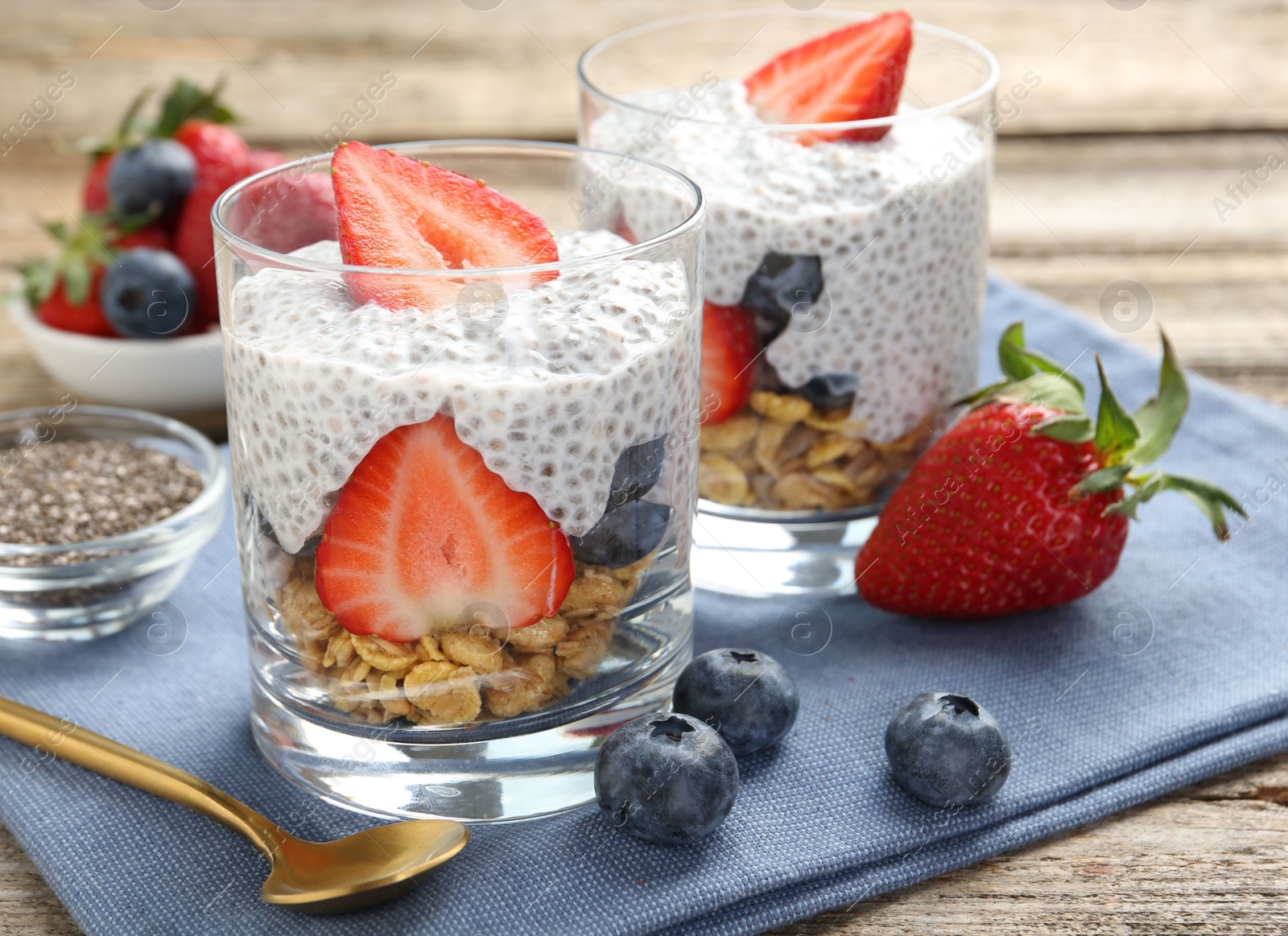 Delicious dessert with chia seeds, yogurt, granola, strawberries and blueberries on wooden table, closeup. Superfood Photo of Delicious dessert with chia seeds, yogurt, granola, strawberries and blueberries on wooden table, closeup. Superfood