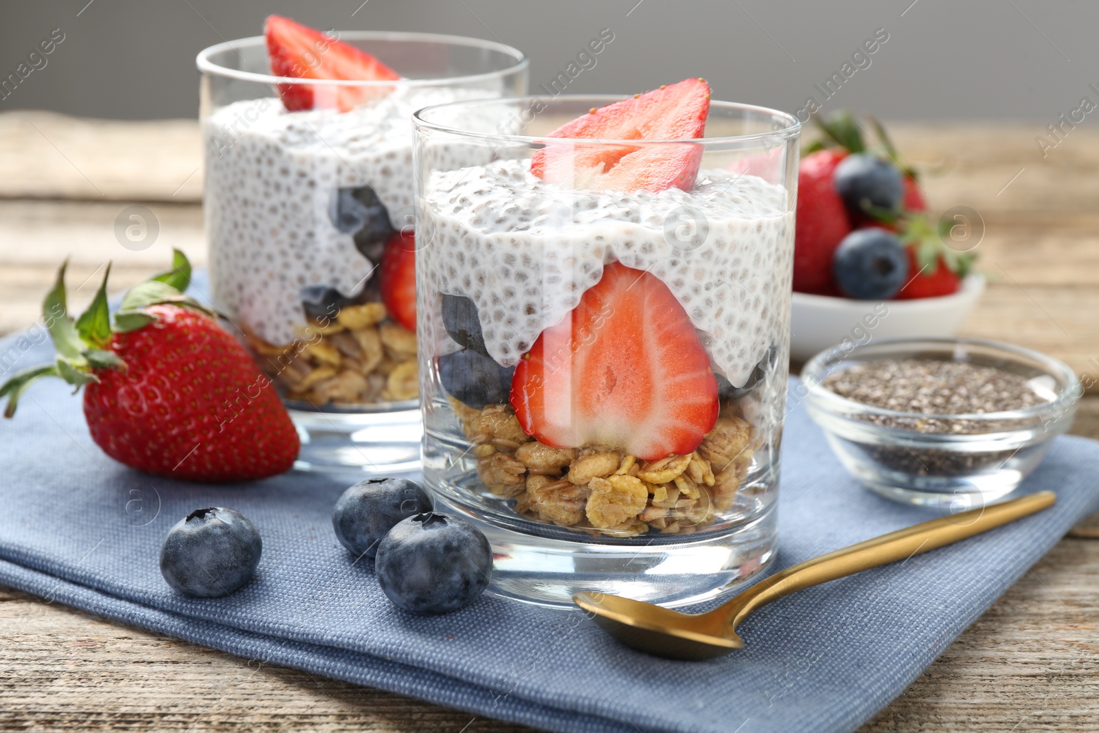 Delicious dessert with chia seeds, yogurt, granola, strawberries and blueberries on wooden table, closeup. Superfood Photo of Delicious dessert with chia seeds, yogurt, granola, strawberries and blueberries on wooden table, closeup. Superfood