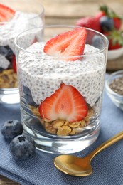 Photo of Delicious dessert with chia seeds, yogurt, granola, strawberries and blueberries on table, closeup. Superfood