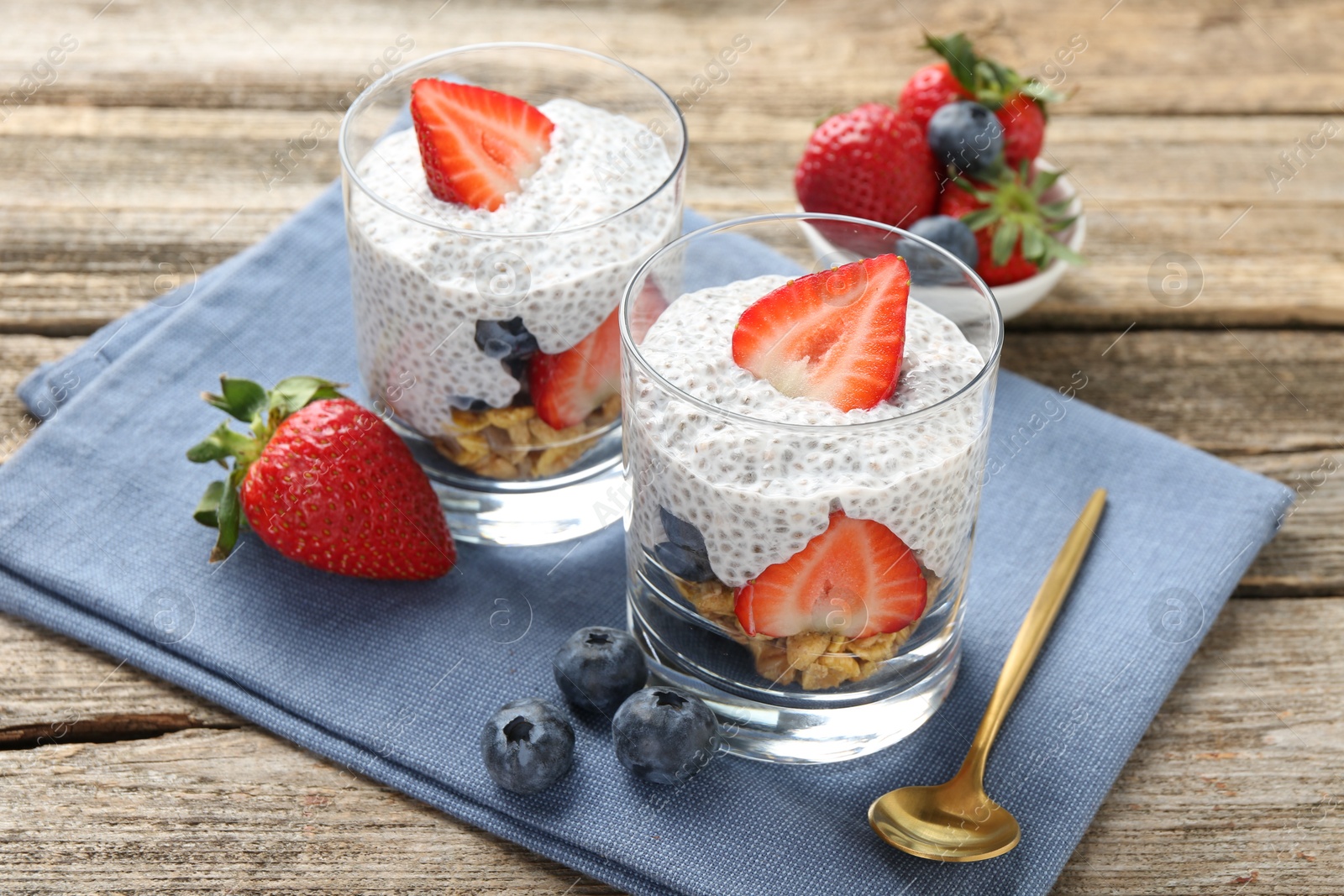 Delicious dessert with chia seeds, yogurt, granola, strawberries and blueberries on wooden table, closeup. Superfood Photo of Delicious dessert with chia seeds, yogurt, granola, strawberries and blueberries on wooden table, closeup. Superfood