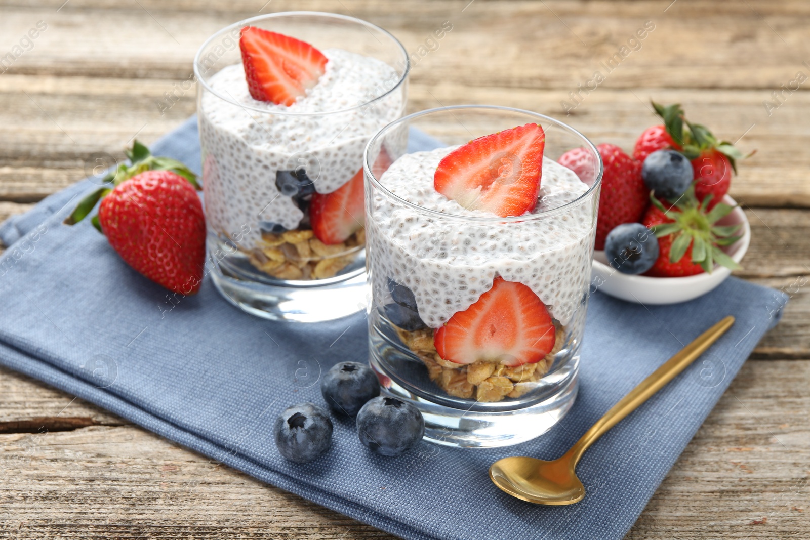 Delicious dessert with chia seeds, yogurt, granola, strawberries and blueberries on wooden table, closeup. Superfood Photo of Delicious dessert with chia seeds, yogurt, granola, strawberries and blueberries on wooden table, closeup. Superfood