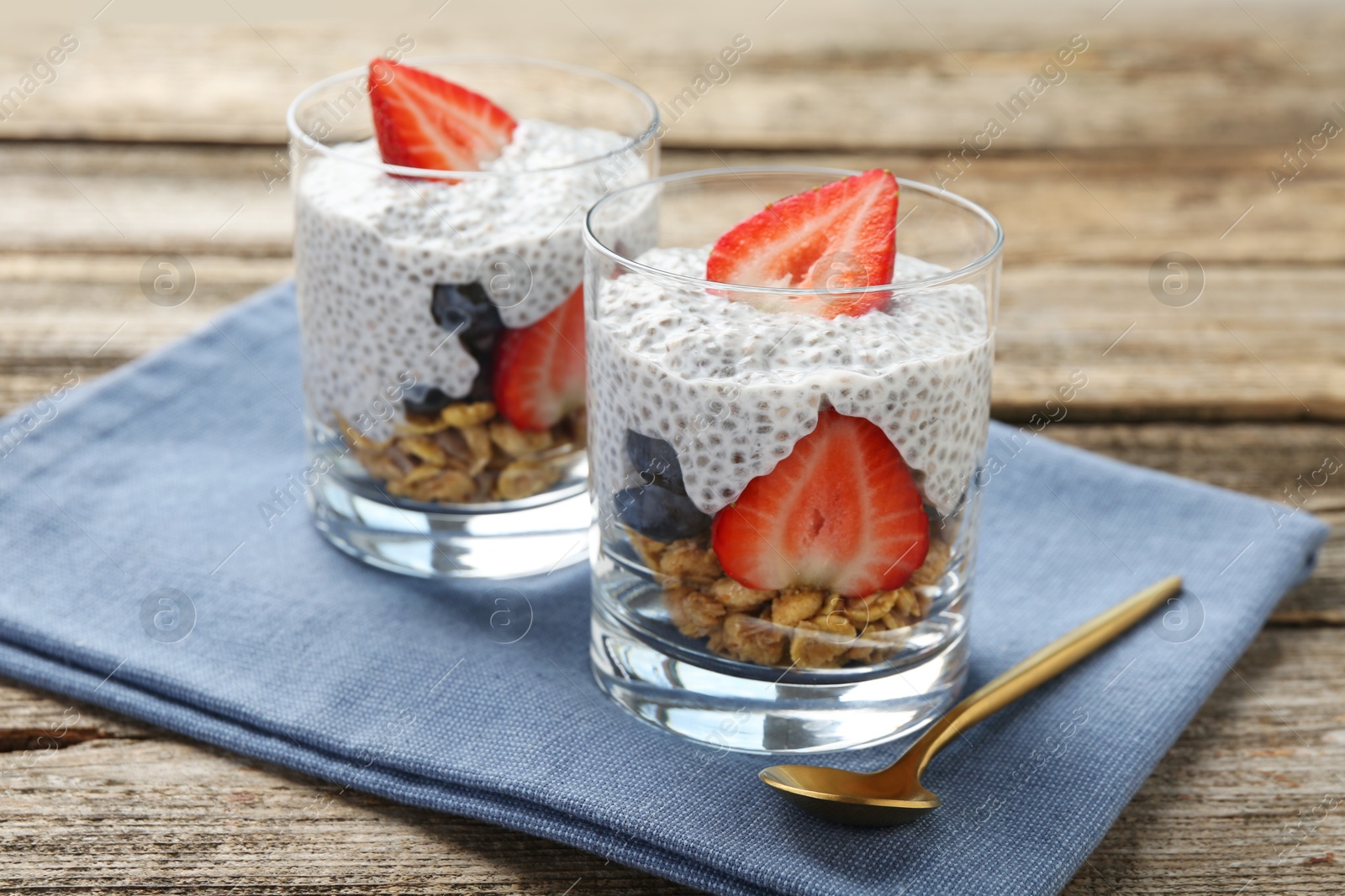 Delicious dessert with chia seeds, yogurt, granola, strawberries and blueberries on wooden table, closeup. Superfood Photo of Delicious dessert with chia seeds, yogurt, granola, strawberries and blueberries on wooden table, closeup. Superfood