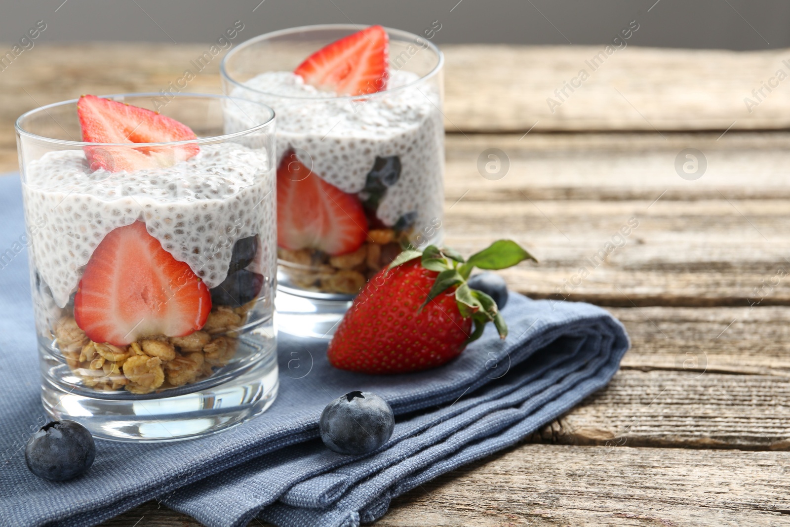 Delicious dessert with chia seeds, yogurt, granola, strawberries and blueberries on wooden table, closeup with space for text. Superfood Photo of Delicious dessert with chia seeds, yogurt, granola, strawberries and blueberries on wooden table, closeup with space for text. Superfood