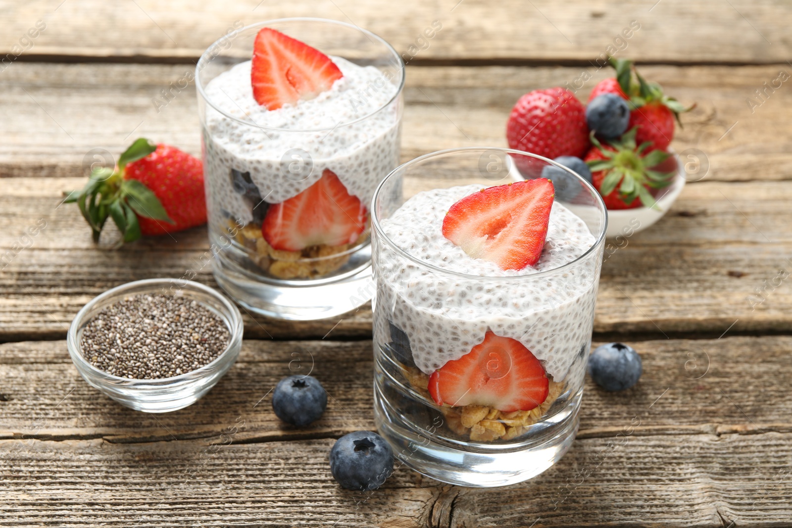 Delicious dessert with chia seeds, yogurt, granola, strawberries and blueberries on wooden table, closeup. Superfood Photo of Delicious dessert with chia seeds, yogurt, granola, strawberries and blueberries on wooden table, closeup. Superfood