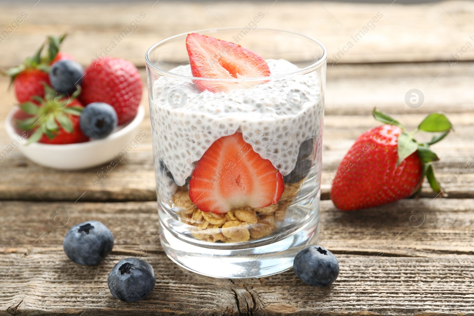 Delicious dessert with chia seeds, yogurt, granola, strawberries and blueberries in glass on wooden table, closeup. Superfood Photo of Delicious dessert with chia seeds, yogurt, granola, strawberries and blueberries in glass on wooden table, closeup. Superfood