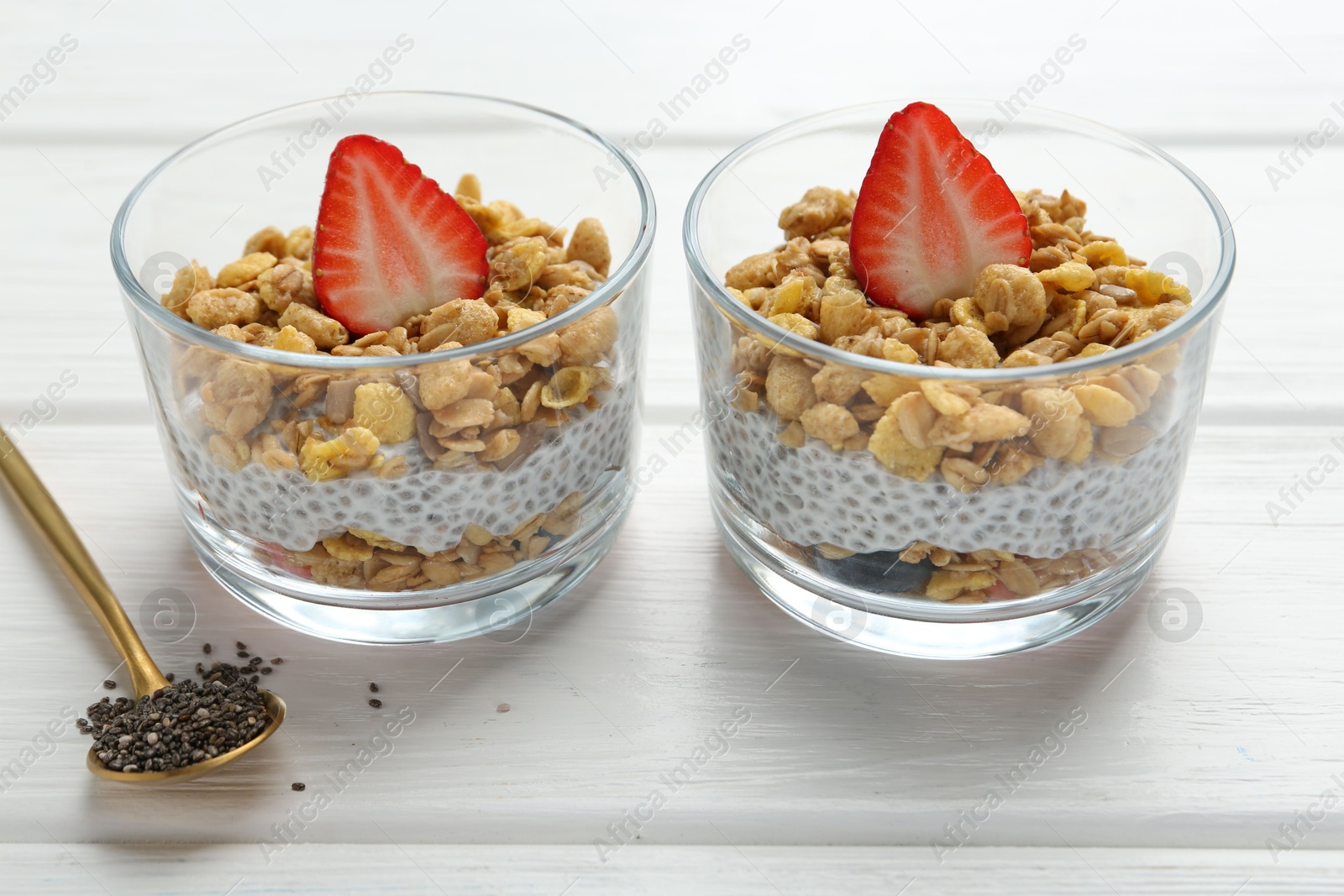 Delicious dessert with chia seeds, yogurt, granola and strawberries in glasses on white wooden table, closeup. Superfood Photo of Delicious dessert with chia seeds, yogurt, granola and strawberries in glasses on white wooden table, closeup. Superfood