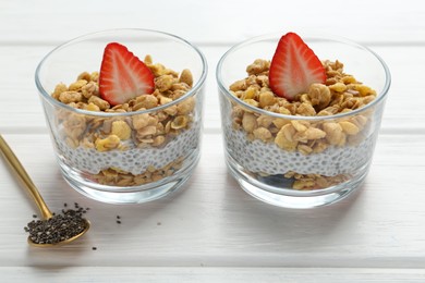 Photo of Delicious dessert with chia seeds, yogurt, granola and strawberries in glasses on white wooden table, closeup. Superfood