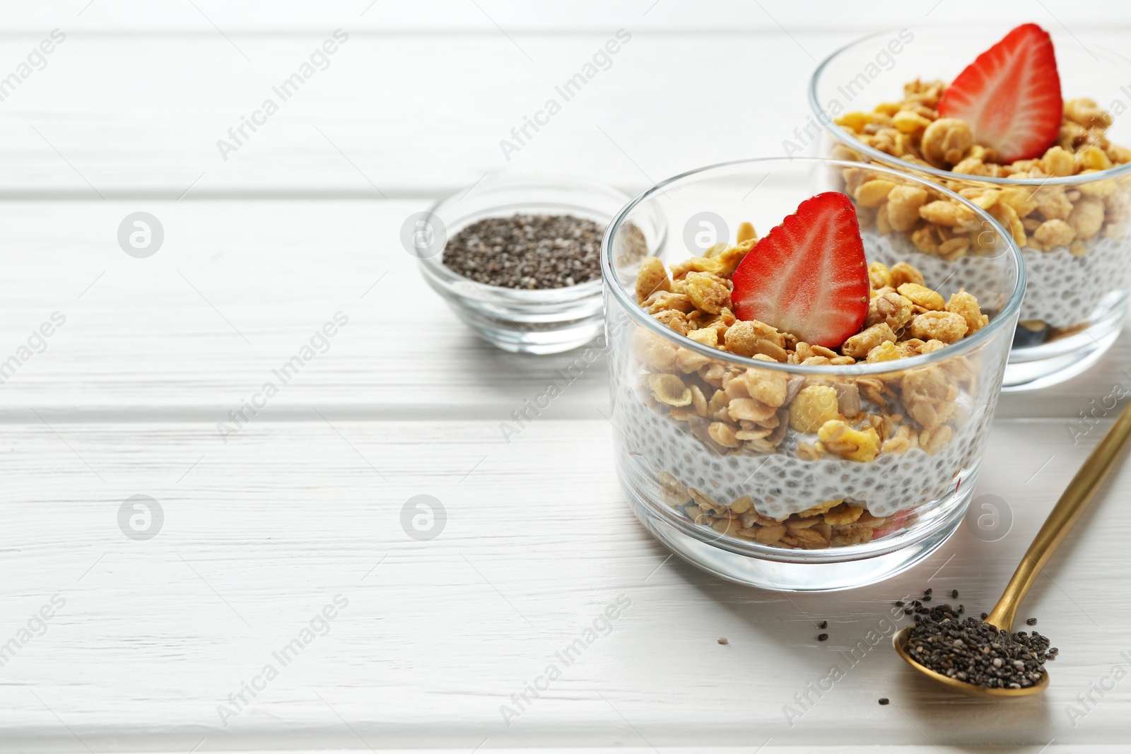 Delicious dessert with chia seeds, yogurt, granola and strawberries in glasses on white wooden table, closeup with space for text. Superfood Photo of Delicious dessert with chia seeds, yogurt, granola and strawberries in glasses on white wooden table, closeup with space for text. Superfood