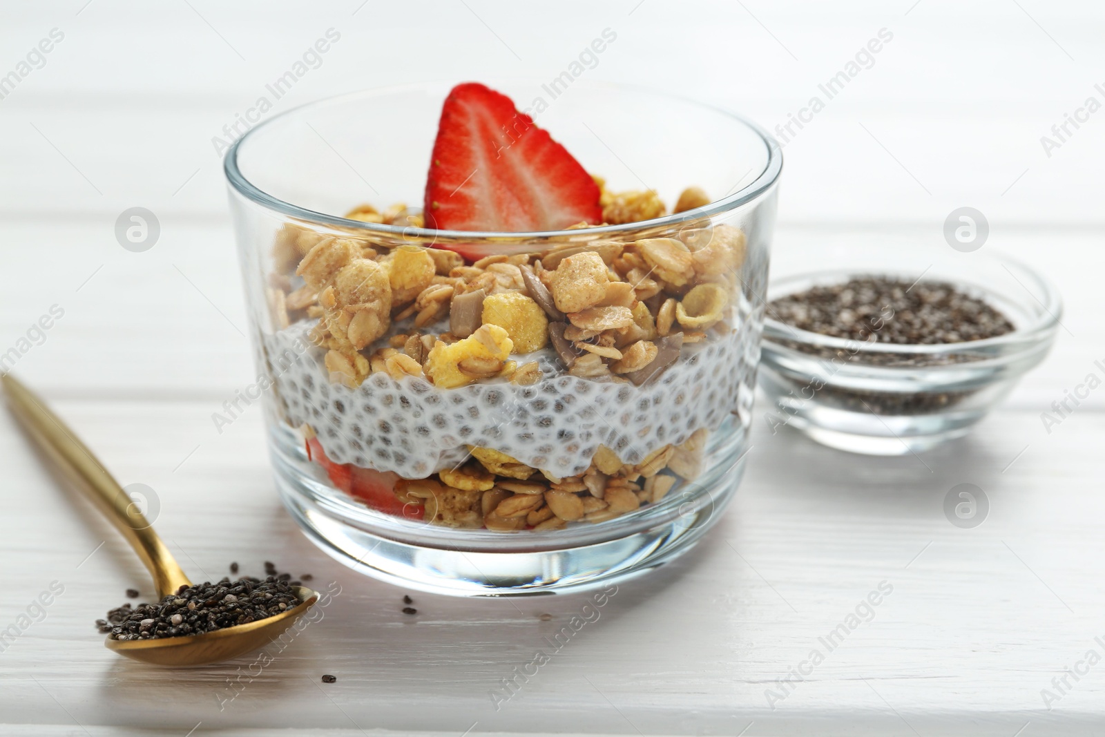 Delicious dessert with chia seeds, yogurt, granola and strawberries in glass on white wooden table, closeup. Superfood Photo of Delicious dessert with chia seeds, yogurt, granola and strawberries in glass on white wooden table, closeup. Superfood