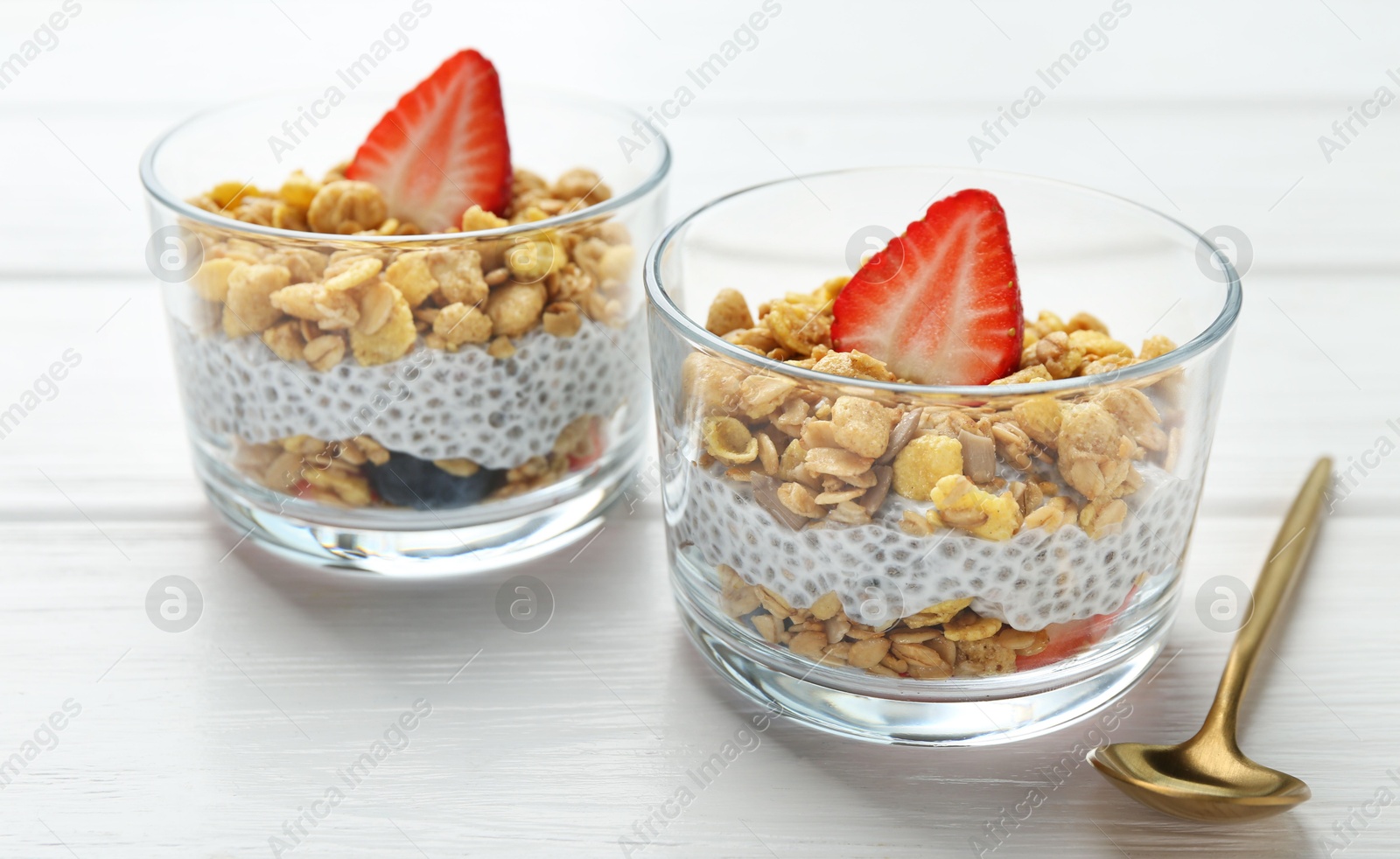 Delicious dessert with chia seeds, yogurt, granola and strawberries in glasses on white wooden table, closeup. Superfood Photo of Delicious dessert with chia seeds, yogurt, granola and strawberries in glasses on white wooden table, closeup. Superfood