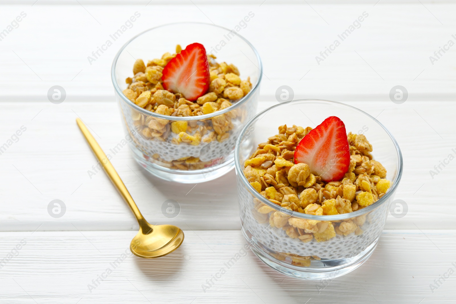 Delicious dessert with chia seeds, yogurt, granola, and strawberries in glasses on white wooden table. Superfood Photo of Delicious dessert with chia seeds, yogurt, granola, and strawberries in glasses on white wooden table. Superfood