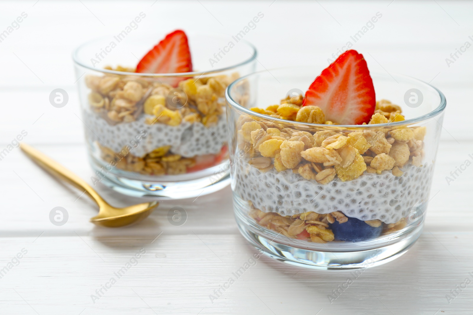 Delicious dessert with chia seeds, yogurt, granola and strawberries in glasses on white wooden table, closeup. Superfood Photo of Delicious dessert with chia seeds, yogurt, granola and strawberries in glasses on white wooden table, closeup. Superfood