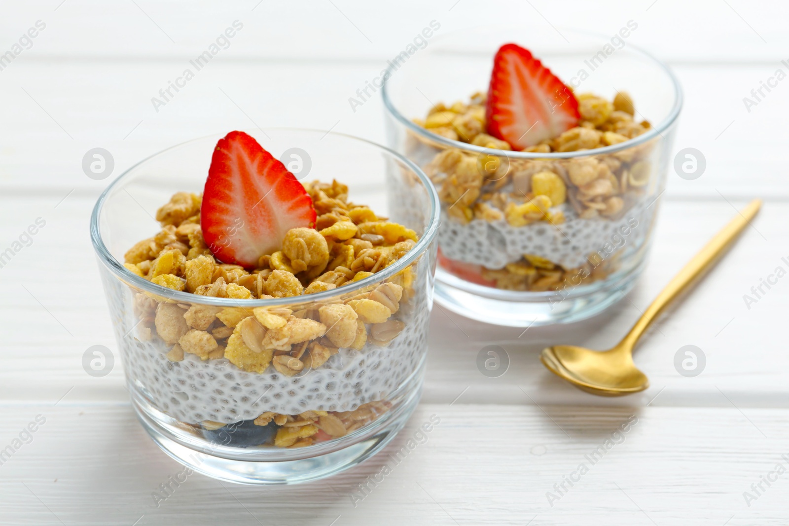 Delicious dessert with chia seeds, yogurt, granola and strawberries in glasses on white wooden table, closeup. Superfood Photo of Delicious dessert with chia seeds, yogurt, granola and strawberries in glasses on white wooden table, closeup. Superfood
