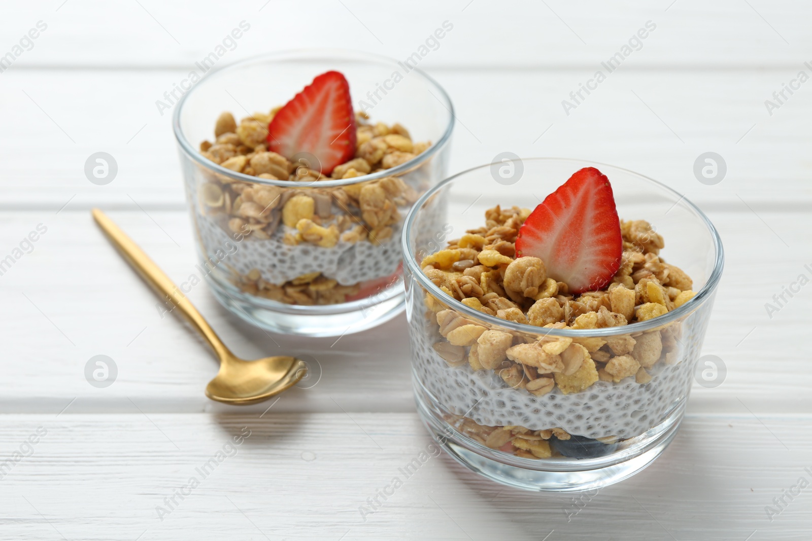 Delicious dessert with chia seeds, yogurt, granola and strawberries in glasses on white wooden table, closeup. Superfood Photo of Delicious dessert with chia seeds, yogurt, granola and strawberries in glasses on white wooden table, closeup. Superfood