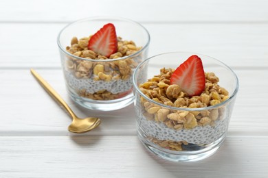 Photo of Delicious dessert with chia seeds, yogurt, granola and strawberries in glasses on white wooden table, closeup. Superfood