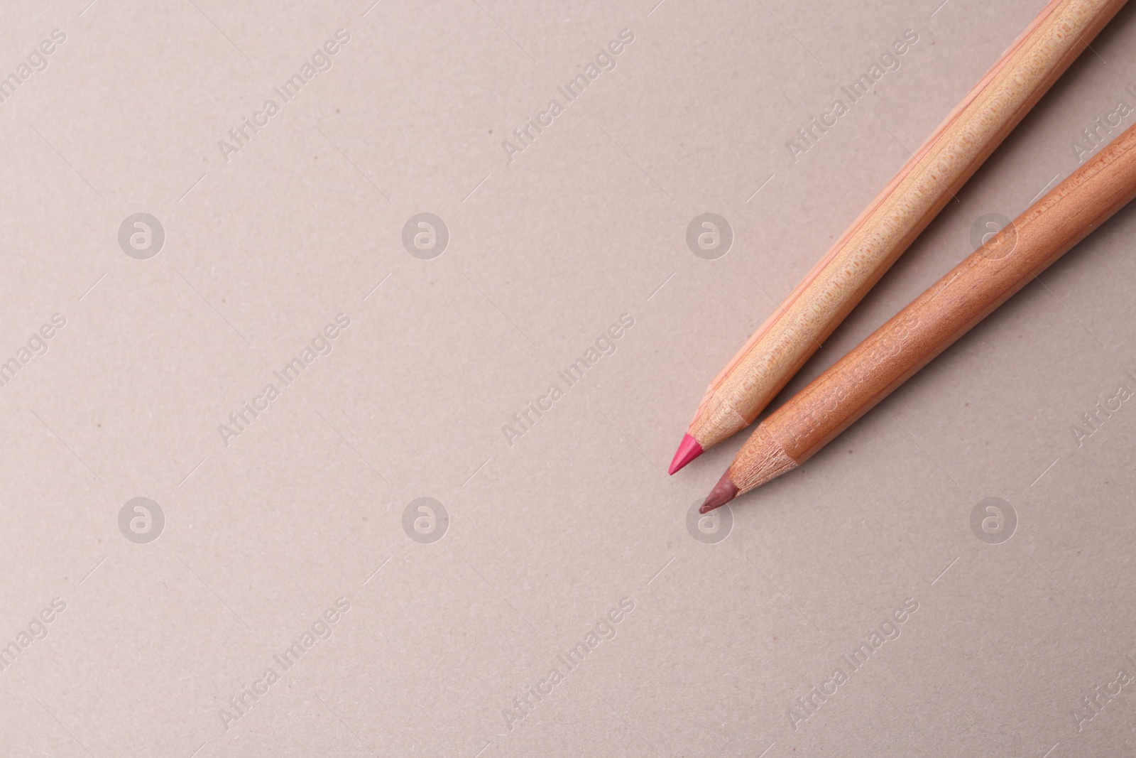 Two lip pencils on light background, top view. Space for text Photo of Two lip pencils on light background, top view. Space for text