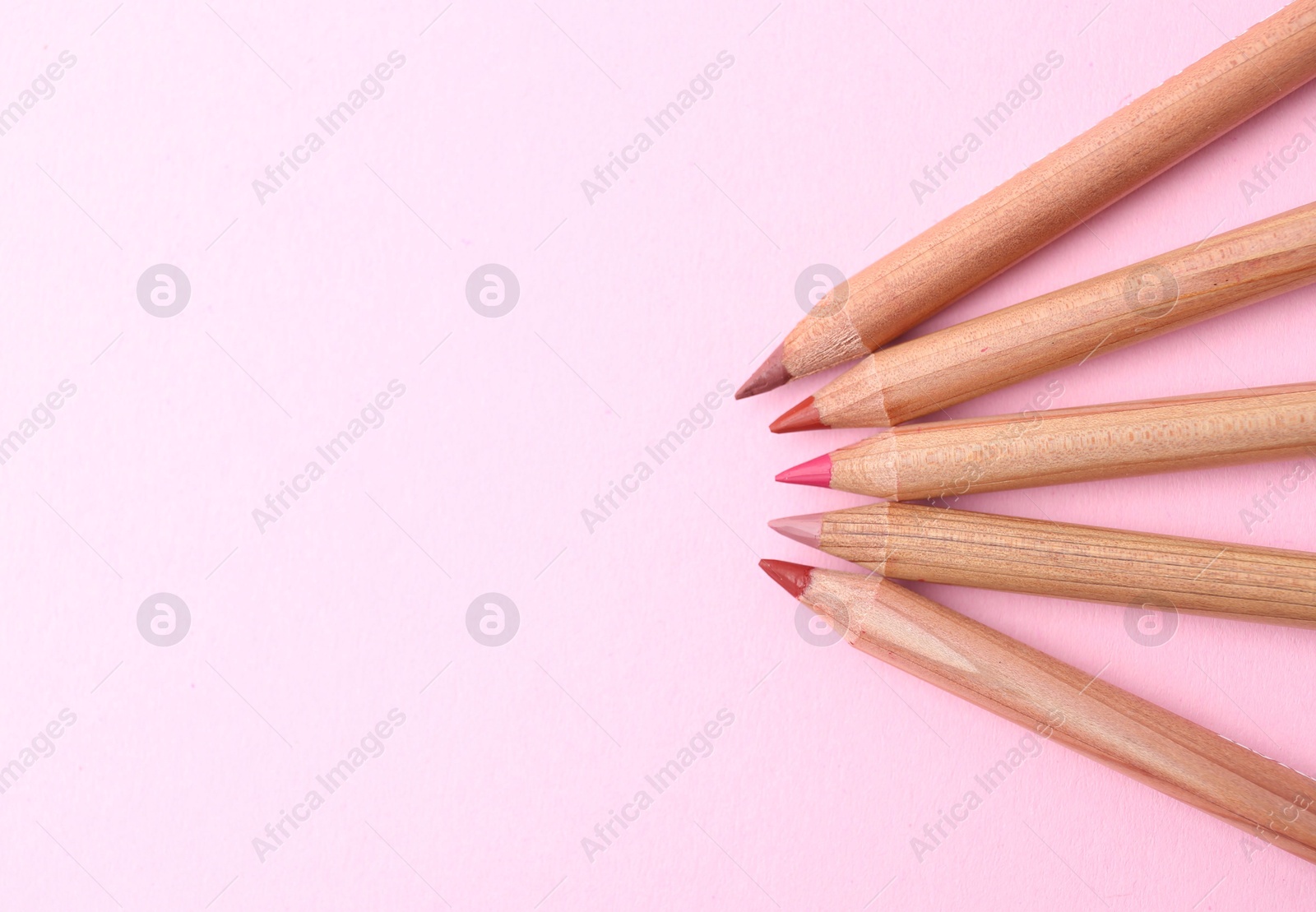 Many different lip pencils on light pink background, flat lay. Space for text Photo of Many different lip pencils on light pink background, flat lay. Space for text