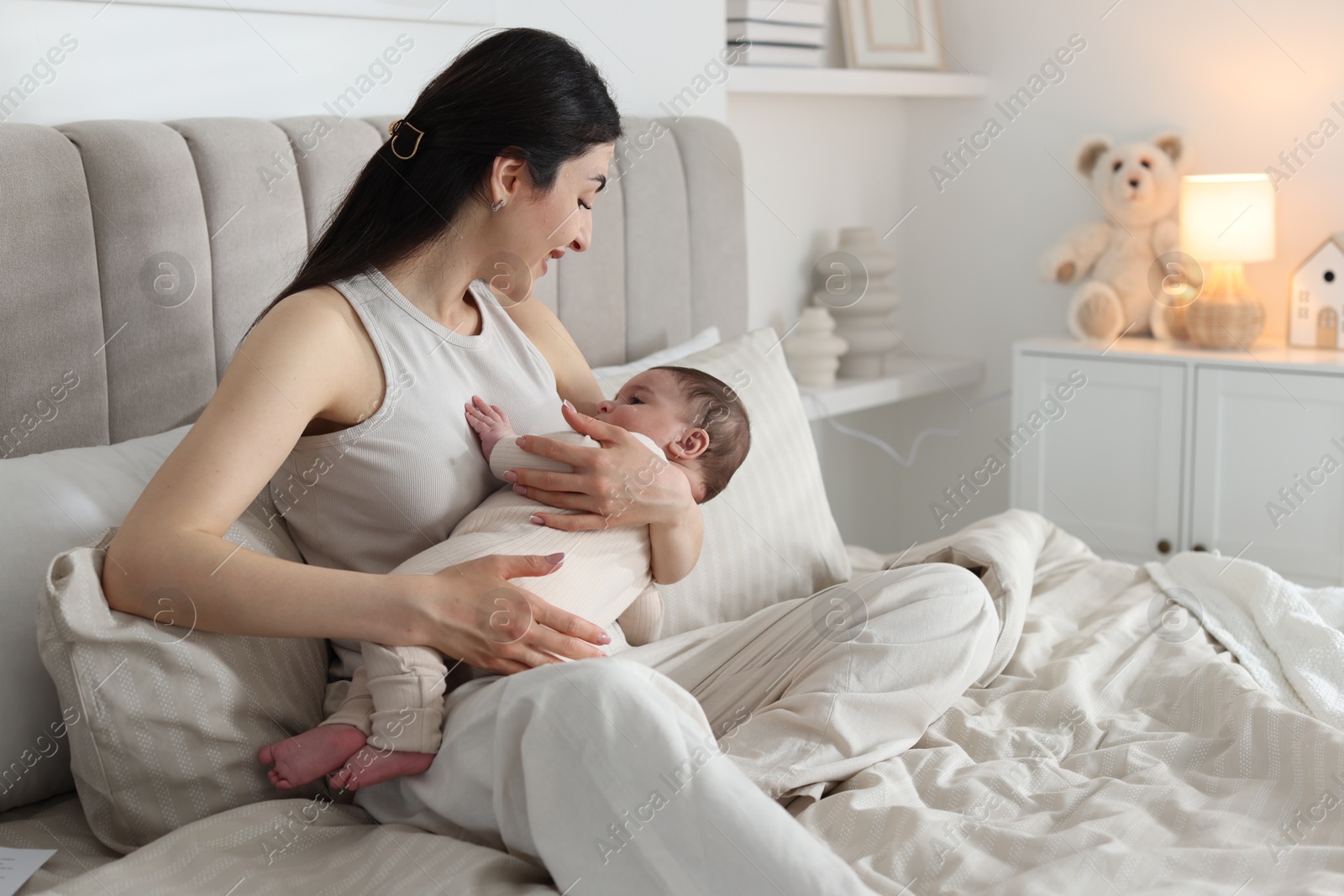 Bedtime. Mother with her cute little baby on bed at home Photo of Bedtime. Mother with her cute little baby on bed at home