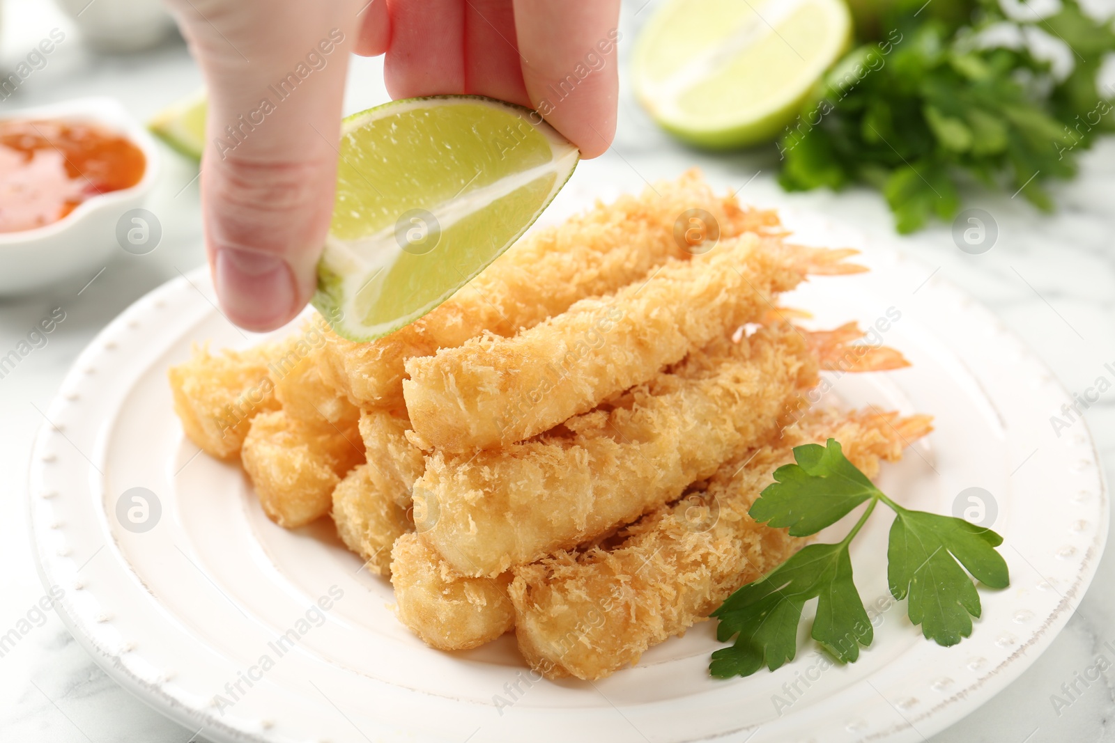 Woman spraying lime juice onto tempura shrimps at table, closeup Photo of Woman spraying lime juice onto tempura shrimps at table, closeup