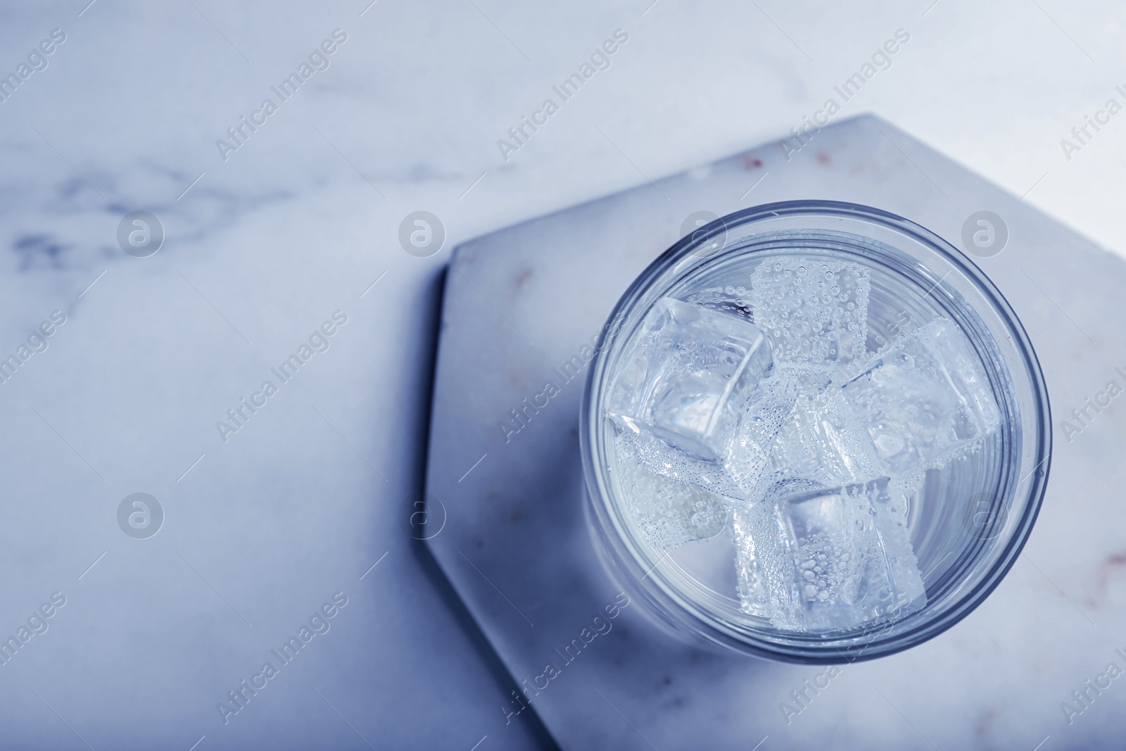 Glass of soda water with ice on white marble table, top view. Space for text Image of Glass of soda water with ice on white marble table, top view. Space for text