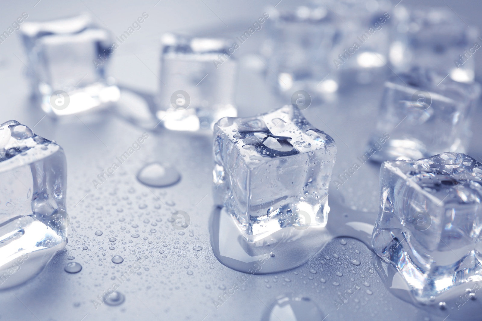 Melting ice cubes and water drops on light blue background, closeup Image of Melting ice cubes and water drops on light blue background, closeup