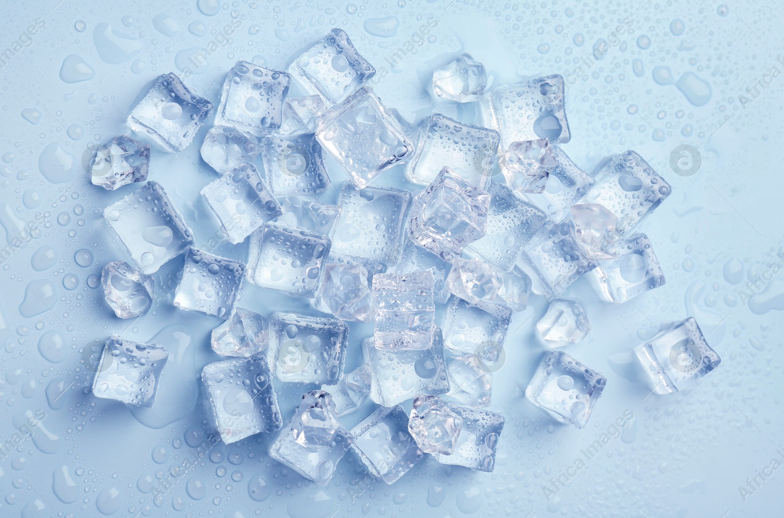 Crystal clear ice cubes on light blue background, flat lay Image of Crystal clear ice cubes on light blue background, flat lay