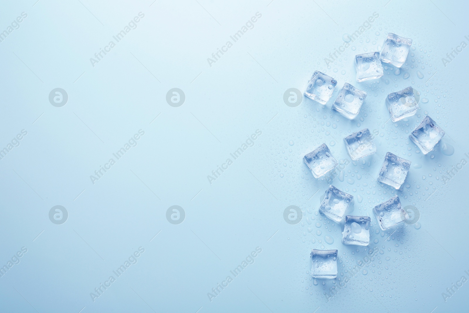 Crystal clear ice cubes on light blue background, flat lay. Space for text Image of Crystal clear ice cubes on light blue background, flat lay. Space for text