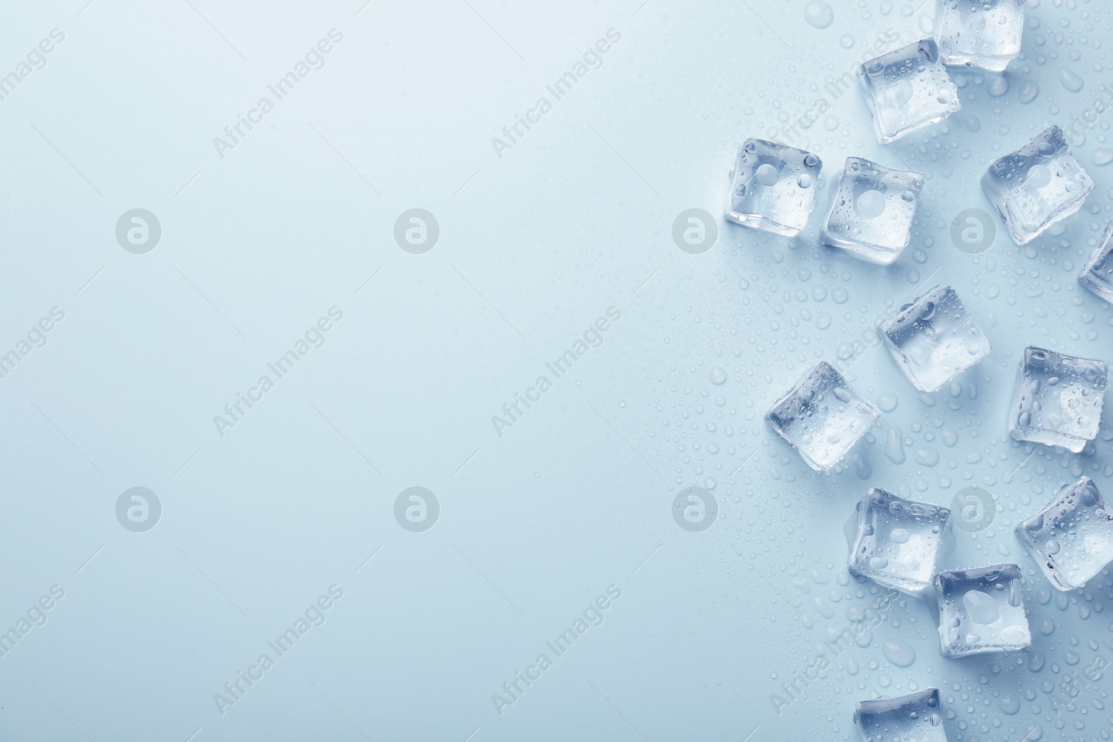 Crystal clear ice cubes on light blue background, flat lay. Space for text Image of Crystal clear ice cubes on light blue background, flat lay. Space for text