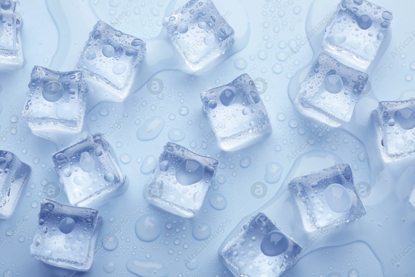 Crystal clear ice cubes on light blue background, flat lay Image of Crystal clear ice cubes on light blue background, flat lay