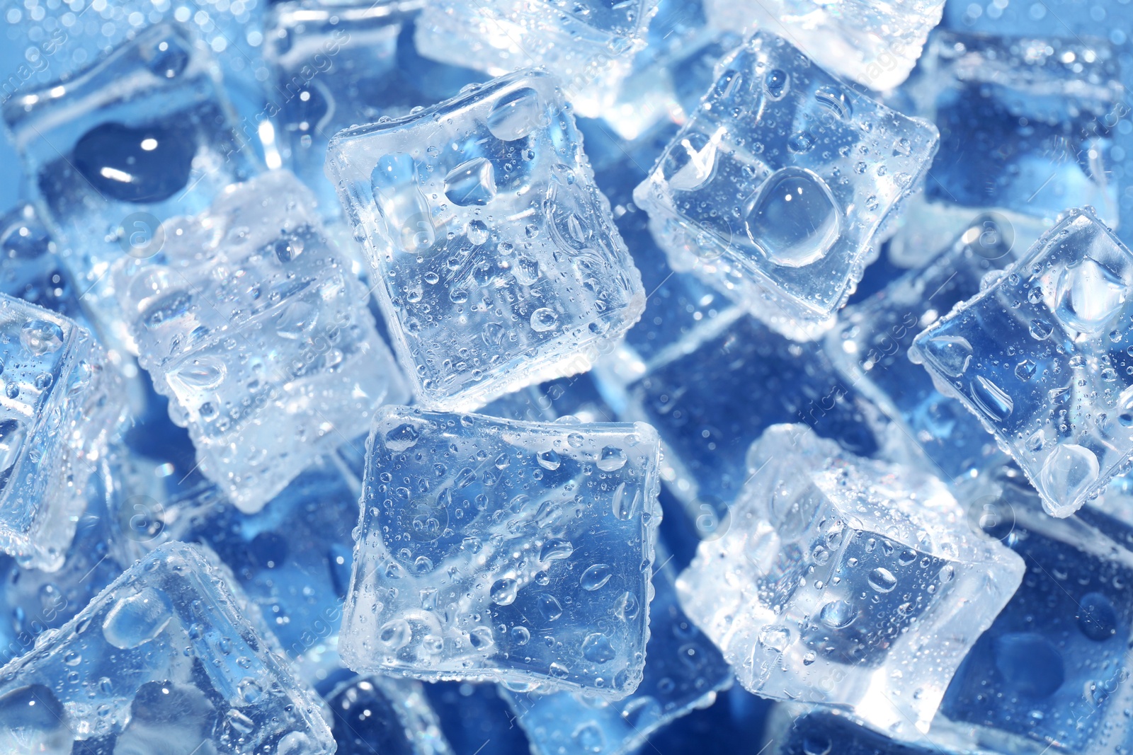 Melting ice cubes and water drops on blue background, above view Image of Melting ice cubes and water drops on blue background, above view
