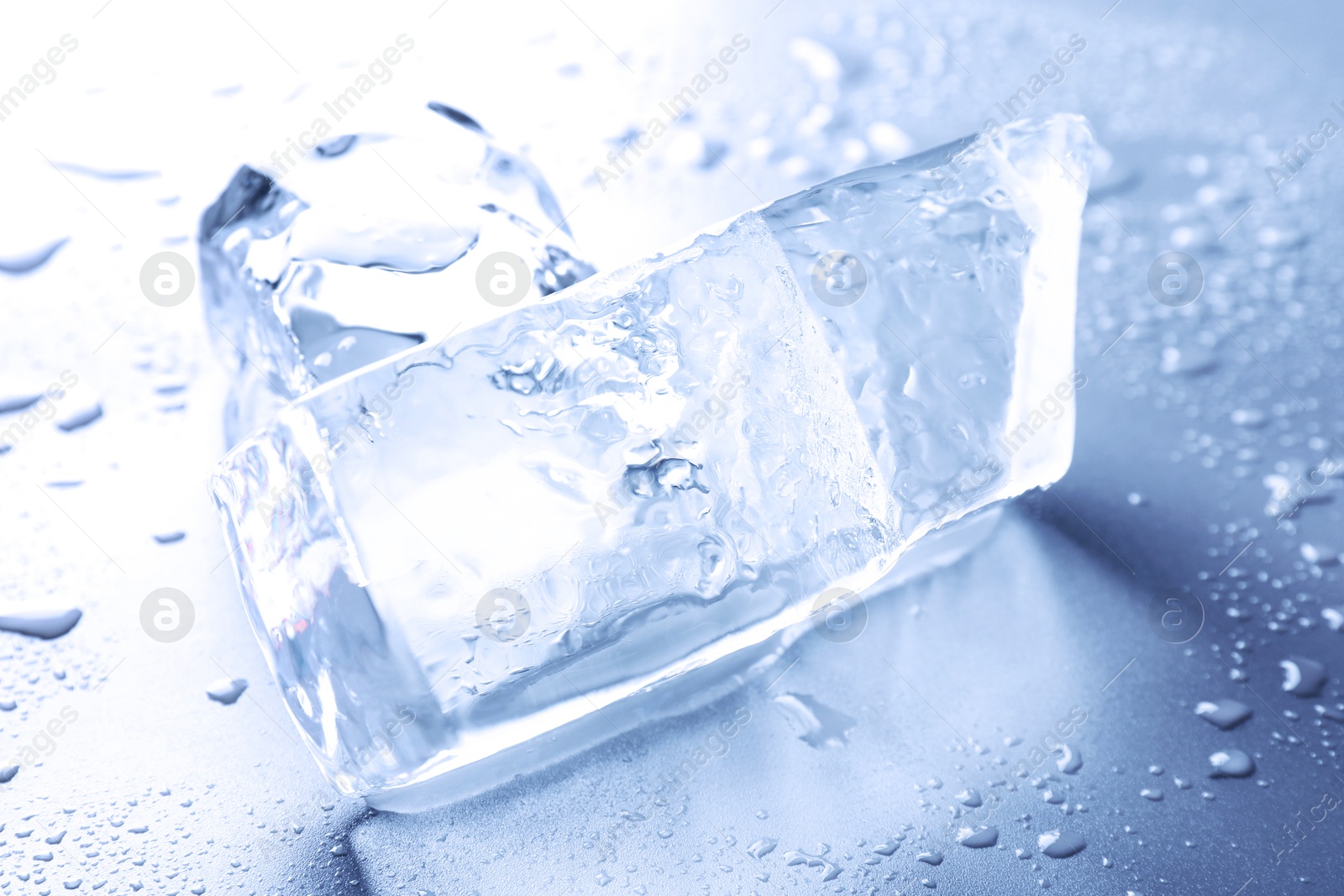 Pieces of clear ice and water drops on light blue table Image of Pieces of clear ice and water drops on light blue table