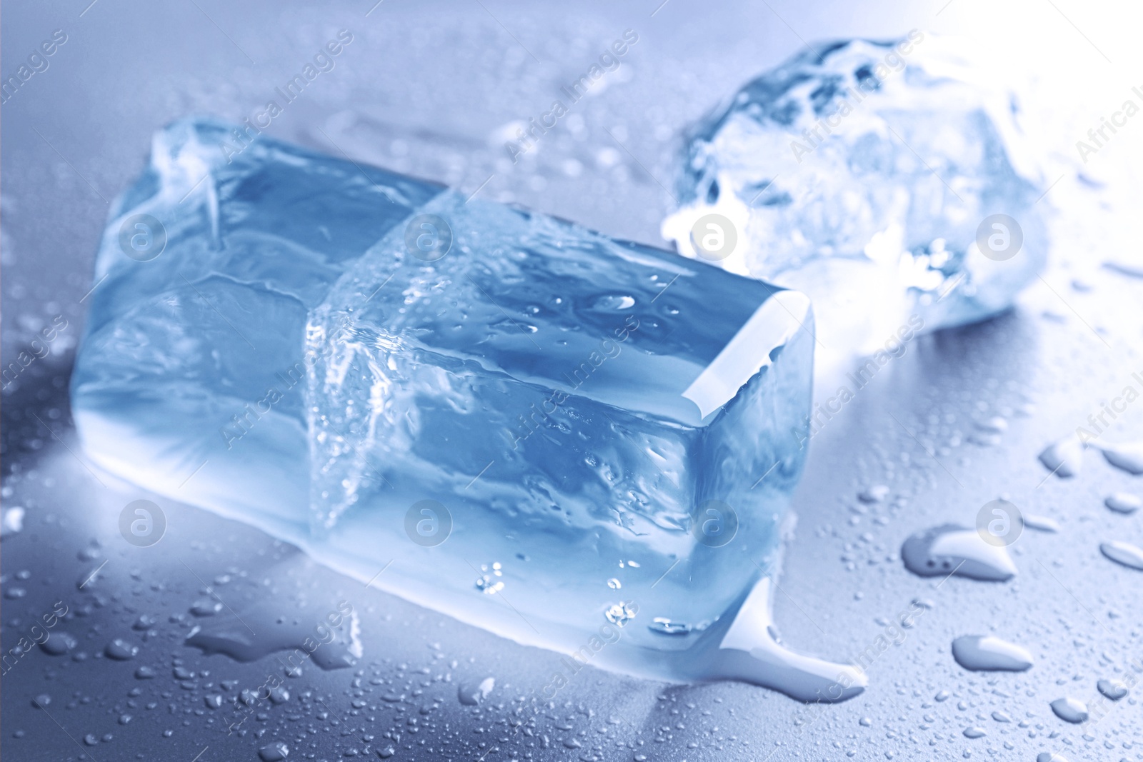 Pieces of clear ice and water drops on light blue table Image of Pieces of clear ice and water drops on light blue table