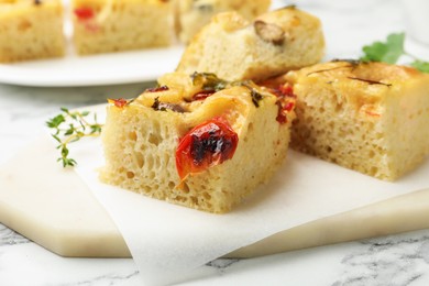 Photo of Pieces of delicious focaccia on white marble table, closeup