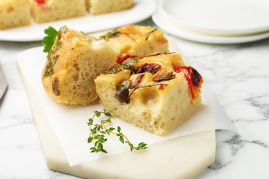 Photo of Pieces of delicious focaccia on white marble table, closeup