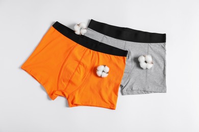 Photo of Comfortable men's underwear and cotton flowers on white background, flat lay