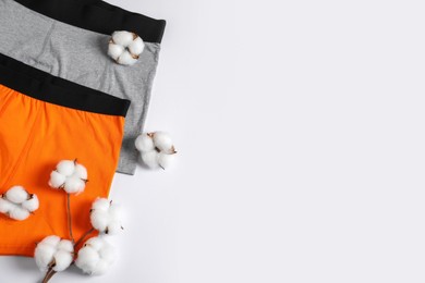 Photo of Comfortable men's underwear and cotton flowers on white background, flat lay. Space for text