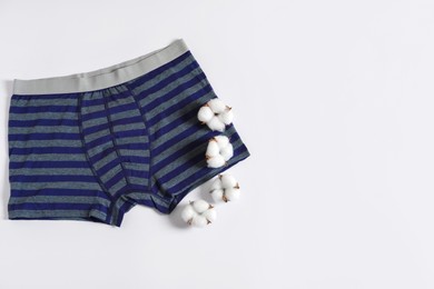 Photo of Comfortable men's underwear and cotton flowers on white background, flat lay. Space for text