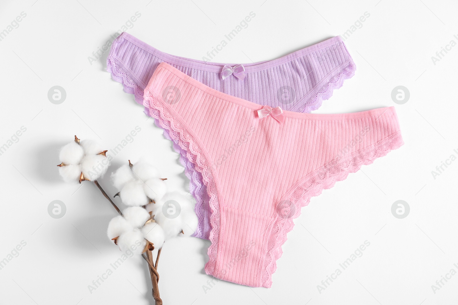 Women's underwear. Beautiful panties and cotton flowers on white background, flat lay Photo of Women's underwear. Beautiful panties and cotton flowers on white background, flat lay