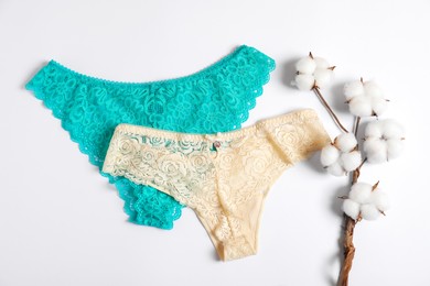 Photo of Women's underwear. Beautiful panties and cotton flowers on white background, flat lay