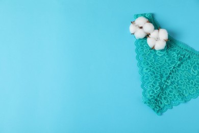 Photo of Women's underwear. Beautiful turquoise panties and cotton flowers on light blue background, top view. Space for text