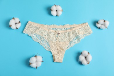 Photo of Women's underwear. Beautiful panties and cotton flowers on light blue background, flat lay