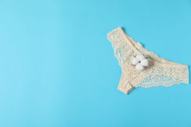 Photo of Women's underwear. Beautiful panties and cotton flower on light blue background, top view. Space for text