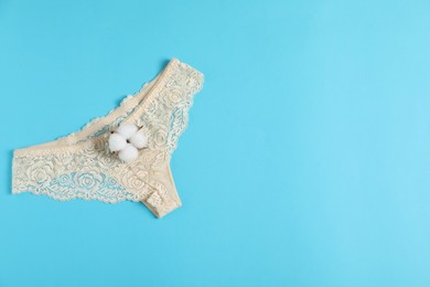 Photo of Women's underwear. Beautiful panties and cotton flower on light blue background, top view. Space for text