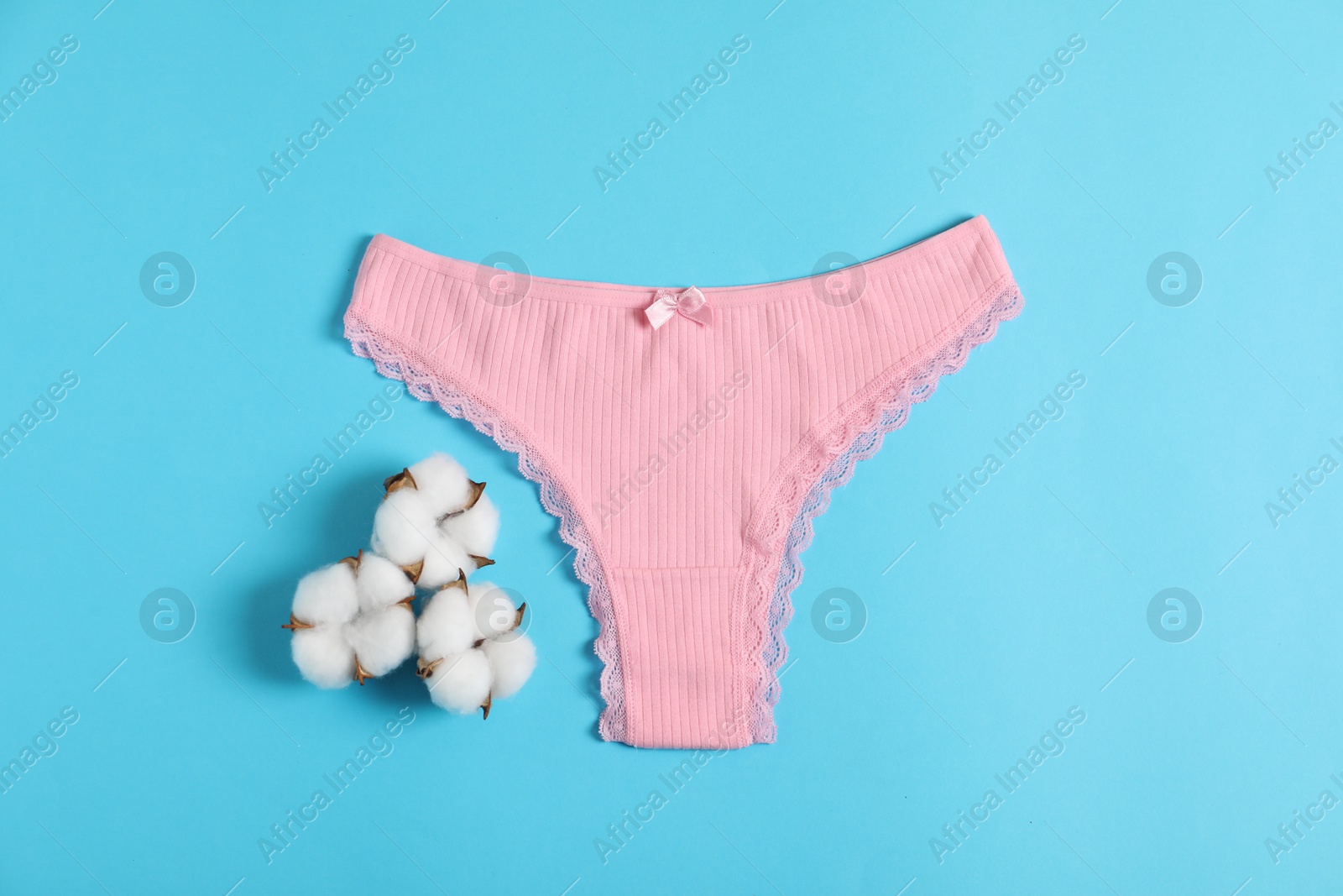 Women's underwear. Beautiful pink panties and cotton flowers on light blue background, top view Photo of Women's underwear. Beautiful pink panties and cotton flowers on light blue background, top view