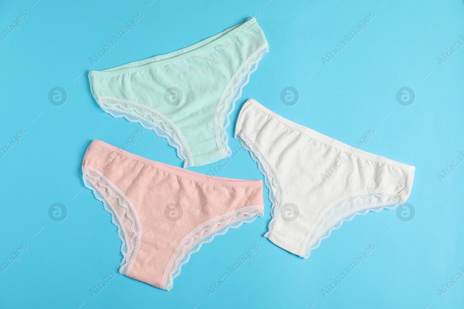 Women's underwear. Beautiful panties on light blue background, flat lay Photo of Women's underwear. Beautiful panties on light blue background, flat lay
