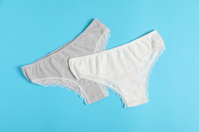 Photo of Women's underwear. Beautiful panties on light blue background, flat lay