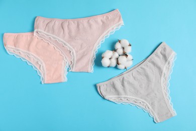 Photo of Women's underwear. Beautiful panties and cotton flowers on light blue background, flat lay