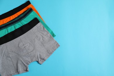 Photo of Comfortable men's underwear on light blue background, flat lay. Space for text