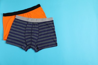 Photo of Comfortable men's underwear on light blue background, flat lay. Space for text